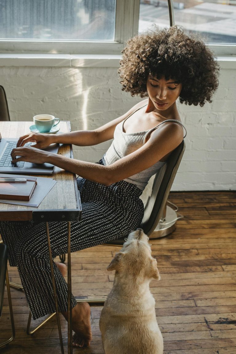 African American woman working on computer with dog near